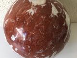 une boule en marbre marron et blanc posée sur une surface blanche