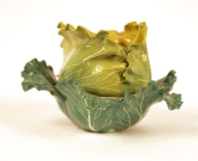 a green bowl with a cabbage in it on a white surface