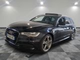 L'Audi break noire est garée dans une grande pièce au sol carrelé en damier.