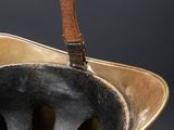 a gold vase with a leather handle on a black background