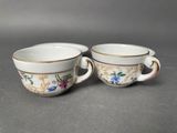 two cups with floral designs on them are sitting on a table