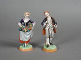 pair of figurines of a man and a woman with baskets of flowers