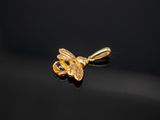 un gros plan d'un pendentif en forme d'abeille dorée sur une surface noire