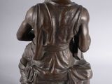 bronze statue of a woman sitting on a box with a flower in her hand