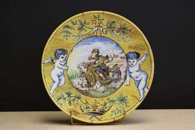 une assiette jaune sur laquelle sont représentés des anges et des chérubins