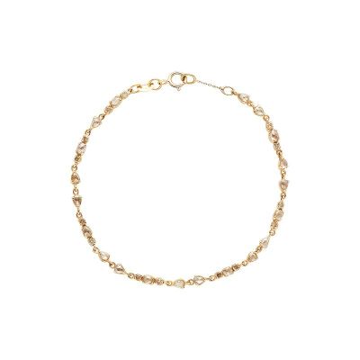 un bracelet en chaîne dorée orné de petites perles sur fond blanc