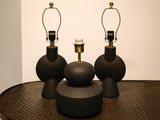 three black vases sitting on top of a table