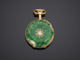 a close up of a green and gold pocket watch on a black surface