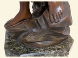 a bronze statue of a person holding a shoe on a marble base