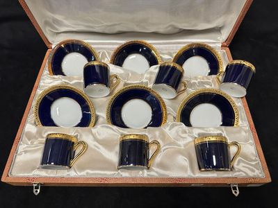 un service de six tasses et soucoupes bleues et blanches, présenté dans une boîte