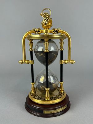 an image of a gold and black hourglass with a dragon on top