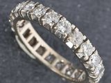 a close up view of a diamond eternity ring on a black surface