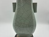 un vase vert posé sur un socle en bois