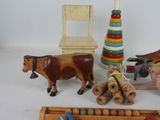 a wooden toy set with a cow, a chair, a stack of toys, and a toy horse