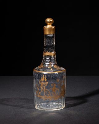 an old glass bottle with a gold lid sitting on top of a table