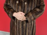 woman in a fur coat standing in front of a red wall