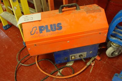 une boîte orange et bleue posée par terre à côté d'une machine bleue et jaune