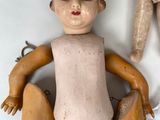 a small doll sitting next to a larger doll