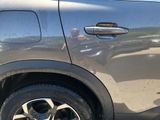 a close up of a car ' s door handle with a reflection of a man in the background