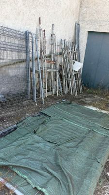 une bâche verte posée par terre devant une clôture
