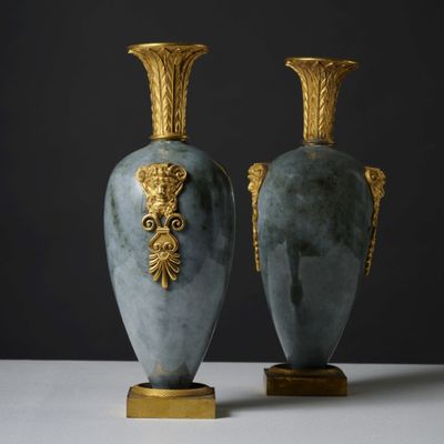 two vases are sitting on a white surface with a black background