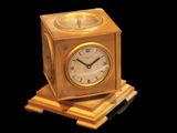 a gold clock sitting on top of a wooden block