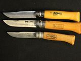 three knives are lined up on a black surface with a wooden handle