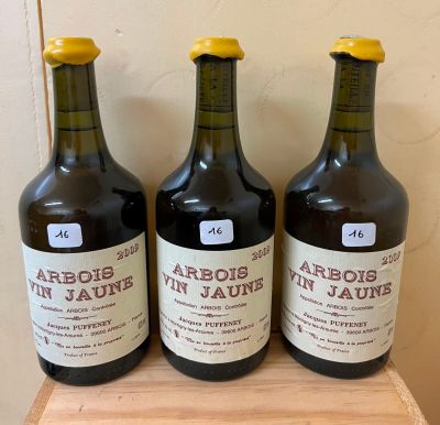 three bottles of wine sit on a wooden shelf in front of a wall