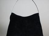 un sac à main noir muni d'une poignée métallique sur fond blanc
