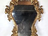 un miroir au cadre doré ouvragé accroché à un mur blanc