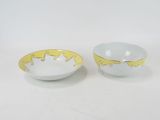 two white and yellow bowls with gold designs on them