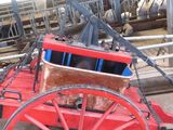a red horse drawn carriage parked in a pen