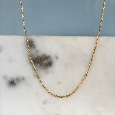 a close up of a gold chain on a marble slab