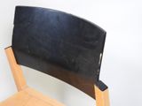 black leather chair with wooden frame against white wall