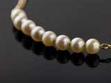a close up of a pearl necklace on a black surface