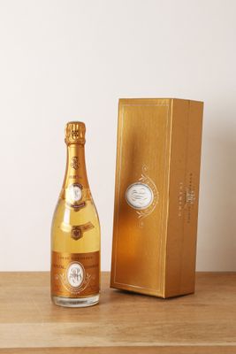 une bouteille de champagne posée sur une table en bois à côté d'un coffret