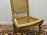 an antique chair with gold paint and wicker seat on a rug