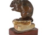 statue of a rat sitting on a piece of bread on a white background