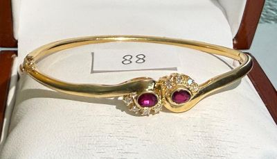 gold bangle with ruby stones and diamonds on display in a jewelry box