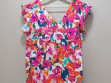a pink and blue floral top hanging on a hanger