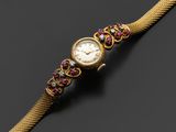 une montre en or sertie de pierres roses et vertes
