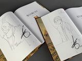 two open books with drawings of people on them sitting on a table
