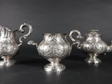 trois théières en métal argenté et une cafetière sur fond noir