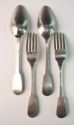 four forks and a spoon on a white table
