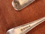 three silver spoons are sitting on a wooden table with a spoon in the middle of them
