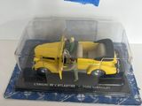 un petit camion jaune avec un homme debout à côté