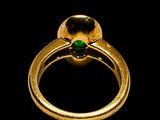 a close up of a gold ring with a green stone