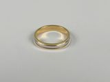 gros plan d'une bague en or et en argent sur une surface blanche