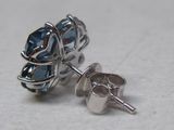 une paire de boucles d'oreilles à clous en cristal bleu posées sur une surface blanche