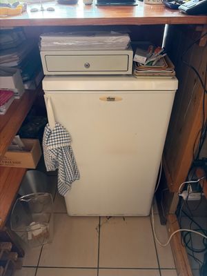 a small white refrigerator in the corner of a kitchen